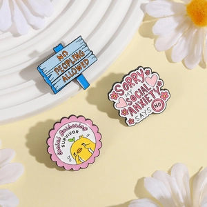Three enamel pins featuring social anxiety themes on a yellow background with white flowers