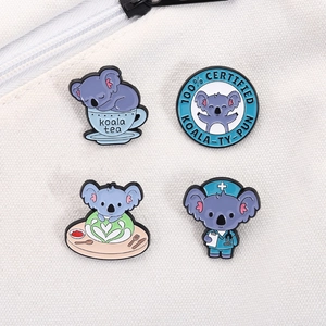Dettaglio di simpatiche spille in smalto koala appuntate su una borsa di tela bianca