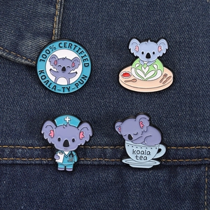 Dettaglio di quattro spille in smalto con koala su denim, temi infermiera e pausa tè carini