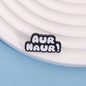 Black and white 'AUR NAUR!' slogan PVC shoe charm on minimalist white display stand