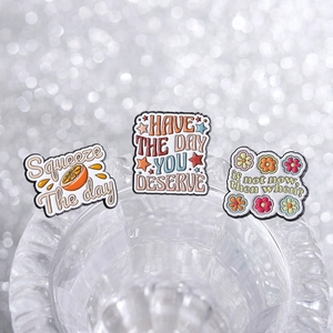 Close-up of enamel pins featuring motivational quotes like Squeeze the Day and floral designs
