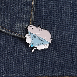 Detailed enamel pin with hippo and cats on blue denim fabric showing geometry puns