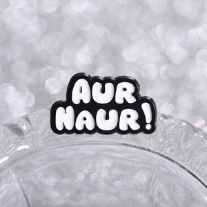 Black and white AUR NAUR geometric badge pin with macro bokeh background lighting