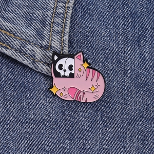 Detail of cute pink skull cat enamel pin with yellow stars on blue denim fabric