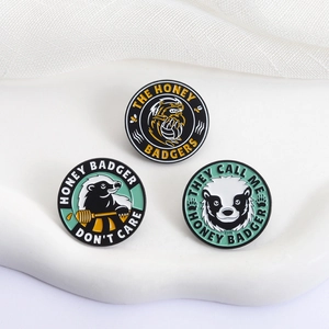 Set of 3 cartoon honey badger enamel pins on a white decorative display stand