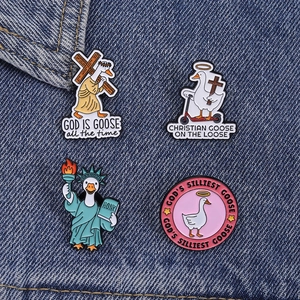 Détail de pins en émail amusants montrant une oie portant une croix sur du denim
