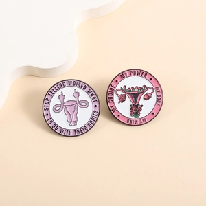 Enamel uterus brooch pins set with feminist slogans on smooth minimalist background