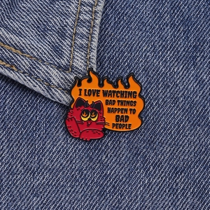 Vue détaillée du pin's chat diable rouge sur tissu denim avec citation gravée