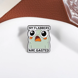 Cute enamel frog pin with My Flabbers Are Gasted text on a white plate background
