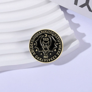 Detail of black enamel bat brooch with gold Ouija board zodiac engraving and yes no text