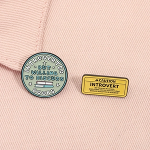 Detail of creative enamel introvert pins featuring book discussion text on pink fabric