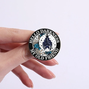 Macro shot of a gothic bat enamel pin with text Hello Darkness My Old Friend