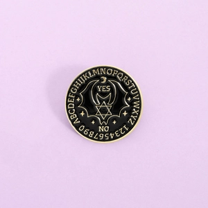 Gothic Ouija board enamel pin with sun moon and bat wings on light purple background