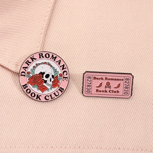 Detail of pink enamel pins featuring a skull rose design and ticket stub book club badge
