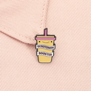 Macro shot of Serotonin Booster enamel pin with yellow cup and pink straw detail