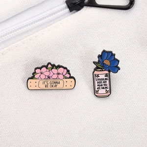 Gros plan de broches émaillées florales avec citation inspirante sur sac en toile