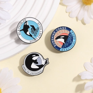 Three-piece set of orca enamel pins with environmental slogans on a minimalist background