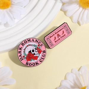 Detail shot of pink enamel skull and flower book club badges set on a minimal background
