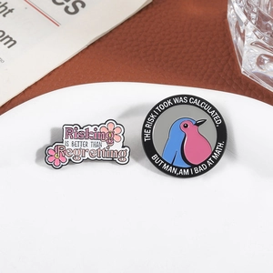 Creative enamel pins with bird motif and motivational quotes on a white plate