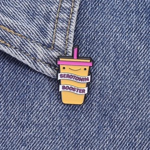 Detail of Serotonin Booster enamel pin shown on dark denim fabric with fine metal textures