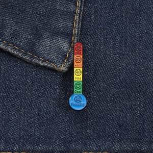 Close-up of rainbow thermometer enamel pin showing mood levels on dark denim jacket