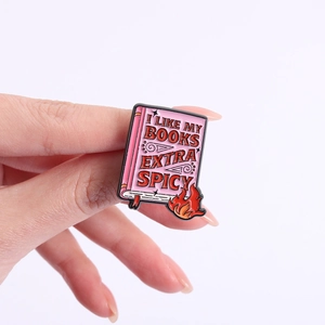 Detail of hand-held enamel book badge with 'I LIKE MY BOOKS EXTRA SPICY' text