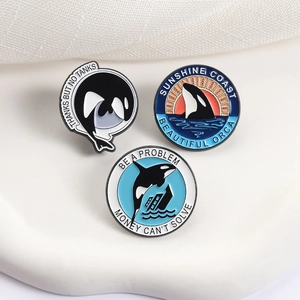Three-piece set of enamel orca pins with environmental theme on white fabric background