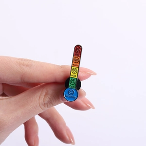 Detailed close-up of a rainbow enamel thermometer pin with mood emojis in hand
