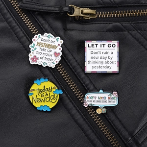 Détail de quatre épingles en émail avec citations inspirantes sur une veste en cuir noir