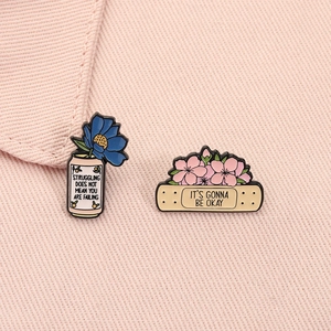 Détail de pins en émail avec citations inspirantes et motifs floraux de printemps