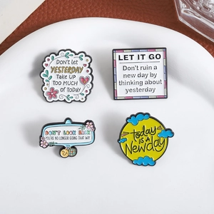 Détails de quatre pin's en émail colorés avec des citations motivantes sur une plaque