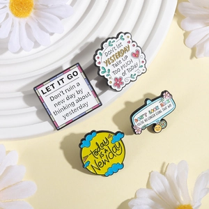 Détail de quatre broches en émail avec des citations inspirantes en anglais et fleurs