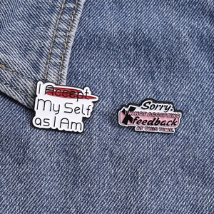 Detail of inspirational metal pins featuring accept phrases pinned on blue denim fabric