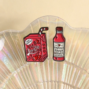 Close-up of Self Love juice box and sauce bottle enamel pins on a shell tray