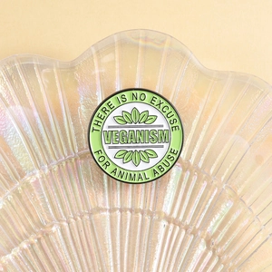 Macro shot of circular enamel veganism pin with leaf motifs and animal rights text
