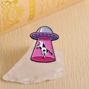 Détail du pin's émaillé OVNI enlevant une vache sur cristal blanc avec lumière douce