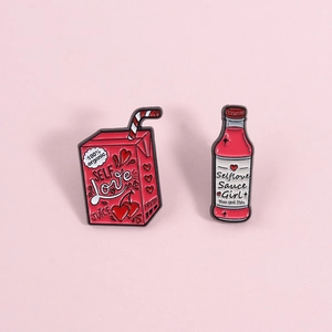 Macro detail of pink enamel pins featuring Self Love juice box and sauce bottle designs