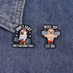 Detail von lustigen Fitness-Anstecknadeln mit Ente und Mops auf blauem Jeansstoff
