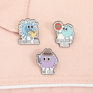 Macro shot of three cute enamel cell lapel pins including NK cell and dendritic cell