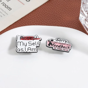 Macro view of inspirational metal brooches with Accept slogans on ceramic tray