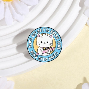Détail de l'épinglette ronde en émail avec chat sur un présentoir floral blanc