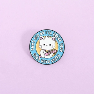 Détail du pin's émaillé rond avec chat de dessin animé et texte Paws Off