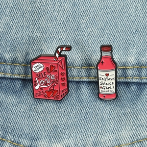 Detailed close-up of pink self love drink pins pinned onto blue denim fabric material