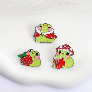 Three cute frog enamel pins featuring king, strawberry, and scholar frog styles