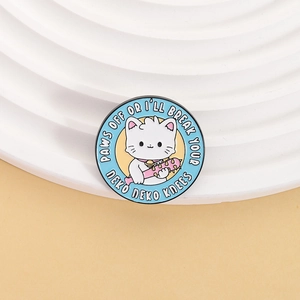 Détail du pin's rond en émail représentant un chat blanc avec une massue rose et fond bleu