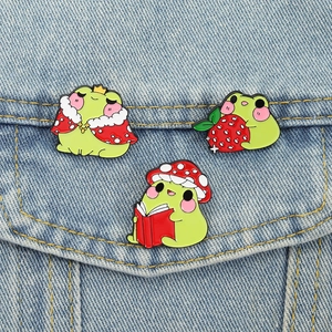 Detailed view of frog enamel pins on denim fabric showing glossy finish and metal lines