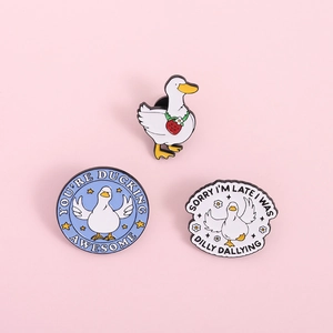 Detailed view of three cute duck enamel pins with humorous quotes on a pink background