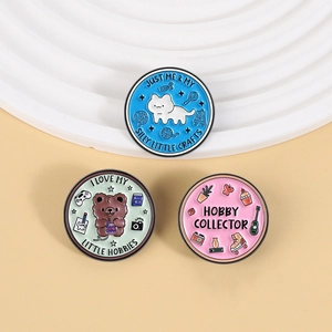 Detailed close-up of three colorful enamel pins featuring cute animals and hobby illustrations
