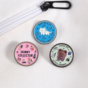 Three cute animal enamel pins on a white canvas bag featuring a cat, bear, and collector theme