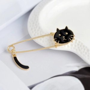 Détail d'une broche épingle à nourrice dorée avec tête de chat noir et queue pendante